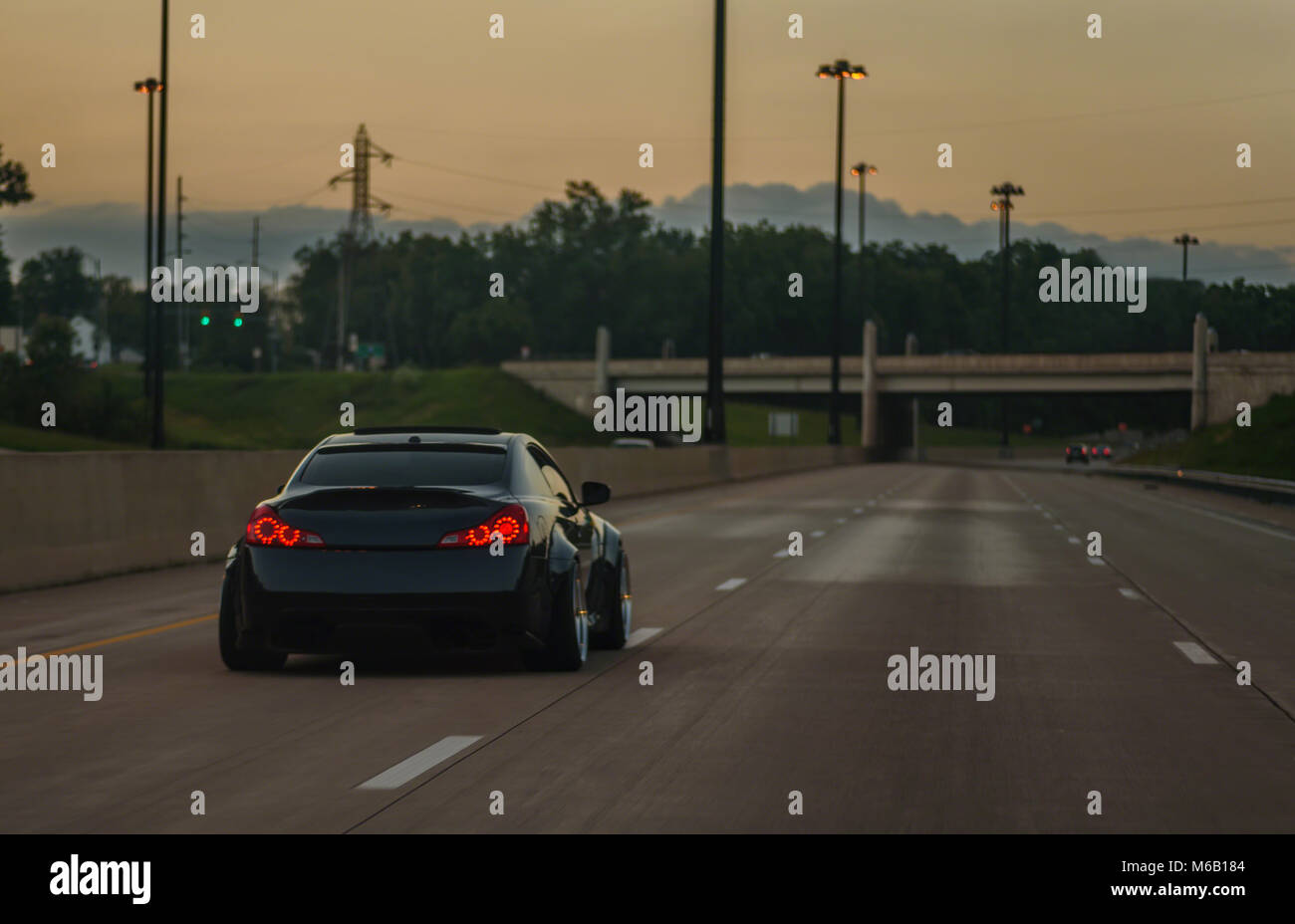 Schwarz angepasst und gesenkt import Sportwagen fahren auf leere Autobahn bei Dämmerung Stockfoto