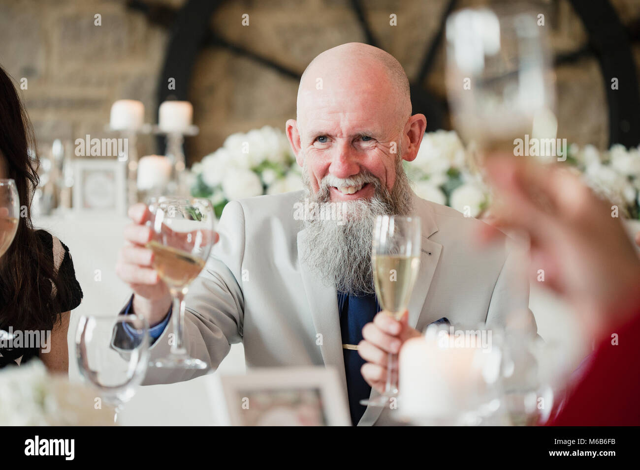 Älterer Mann hebt sein Glas mit einem Toast auf seine Töchter Hochzeit Mahlzeit. Stockfoto
