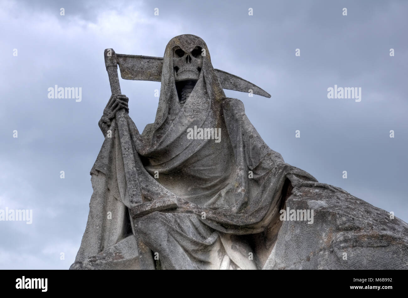 Der Tod personifiziert als Skelett mit Umhang und Sense dieses Bild der verwitterte Skulptur auf dem Friedhof getroffen wurde. Stockfoto