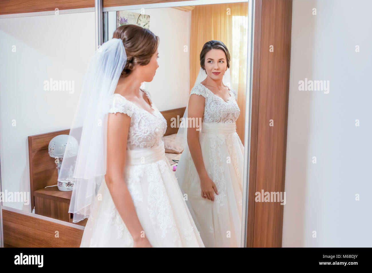 Schöne junge Braut im Brautkleid loking Spiegel. Schwerpunkt in den Spiegel! Stockfoto