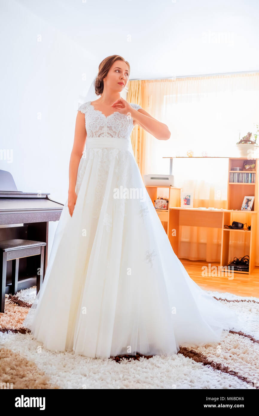 Schöne junge Braut im Brautkleid im Wohnzimmer Stockfoto