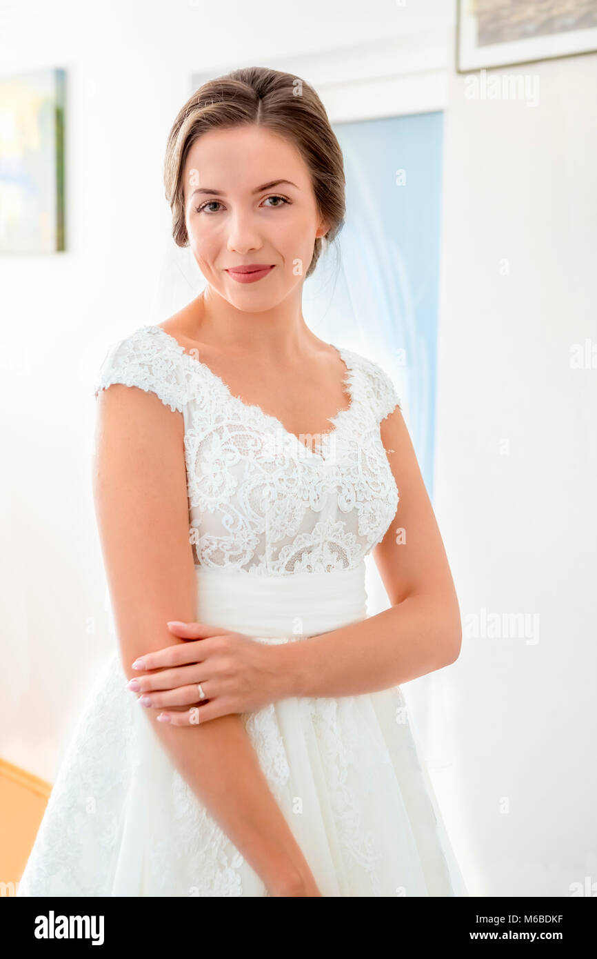 Schöne junge Braut im Brautkleid im Wohnzimmer Stockfoto