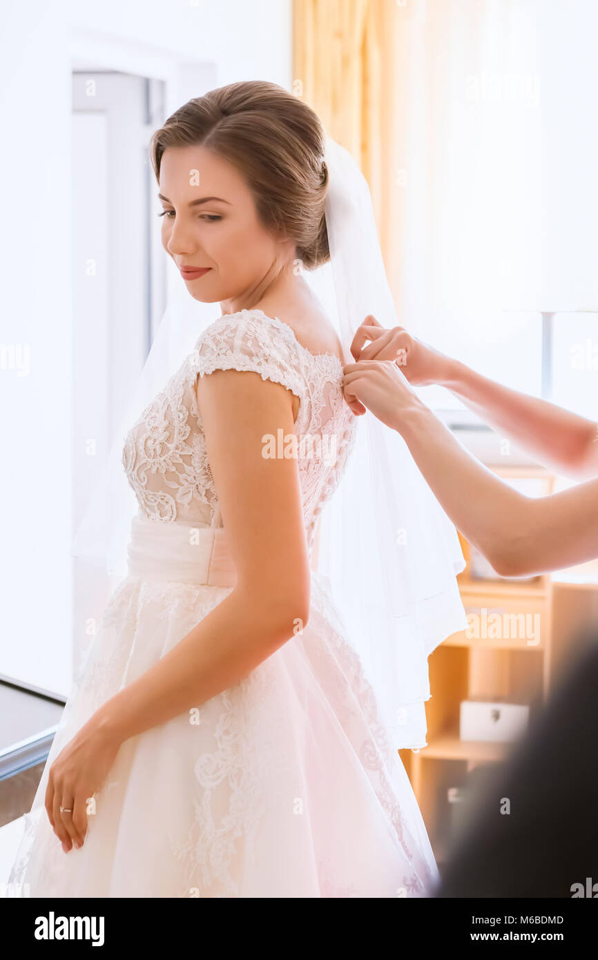 Hilft die Braut ihr Brautkleid anziehen Stockfoto