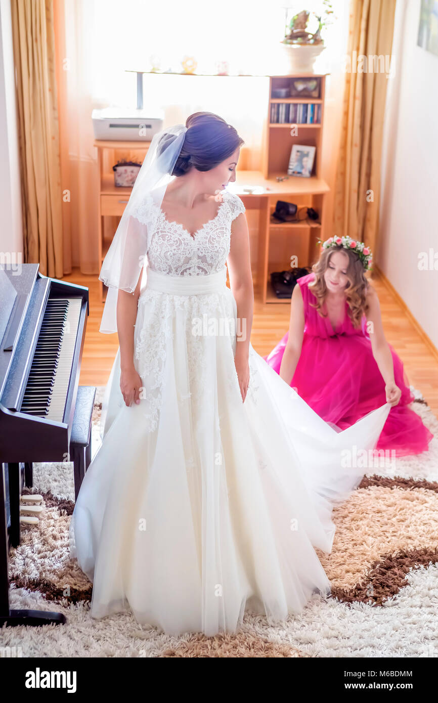 Hilft die Braut ihr Brautkleid anziehen Stockfoto