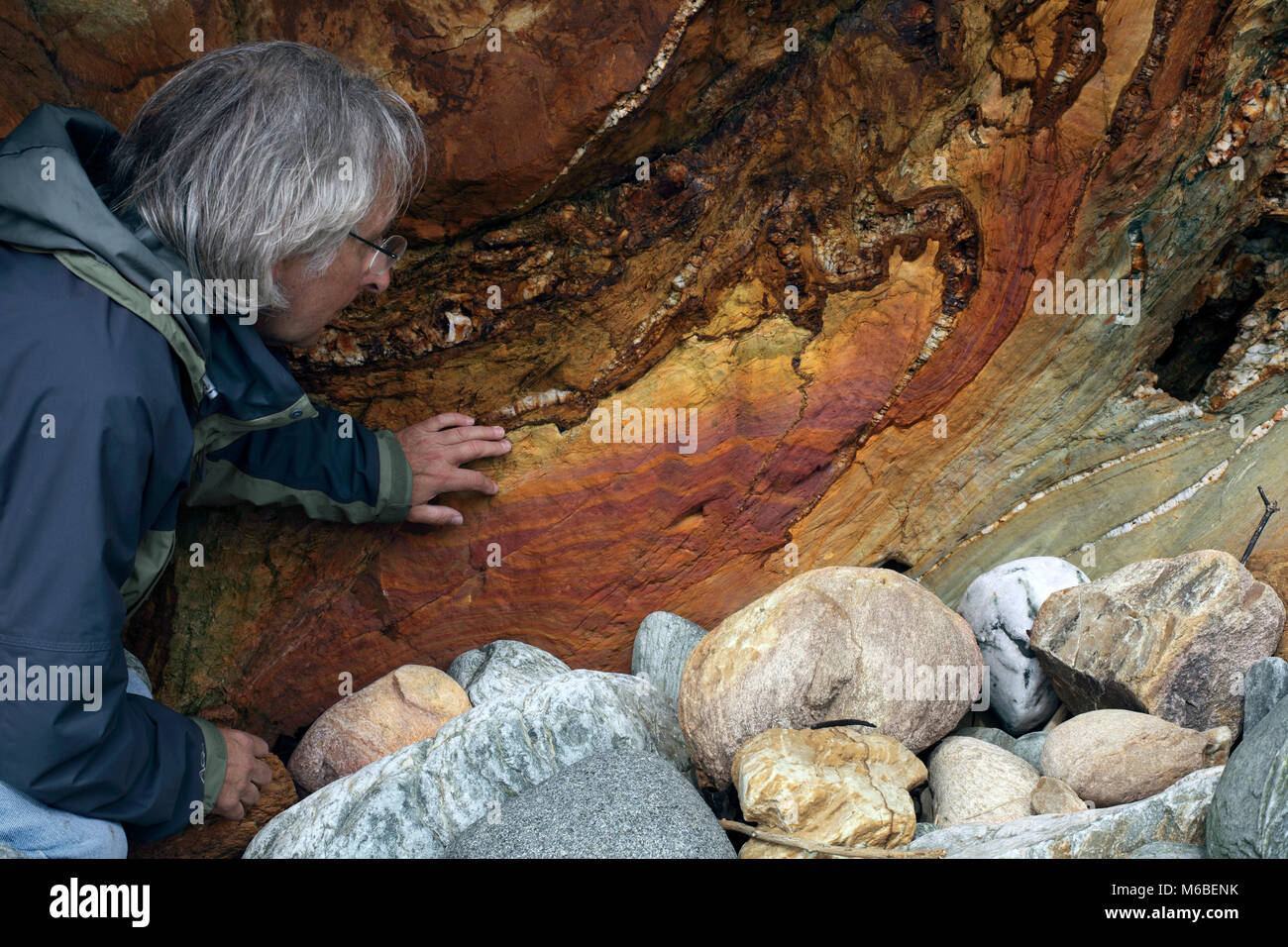 Rock rot eingefärbt durch Eisen aus Erz Gelaugt-Klippe an der Küste von Porth Saint, in der Nähe der Rhoscolyn, anglesey, Wales. Stockfoto