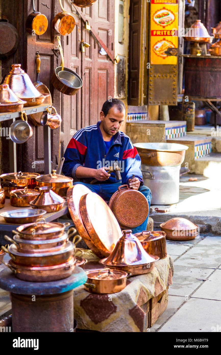 Messinggeschirr artisan vor einem Geschäft auf einem Topf in den Souks der alten Medina von Fes, Marokko arbeiten Sitzen Stockfoto