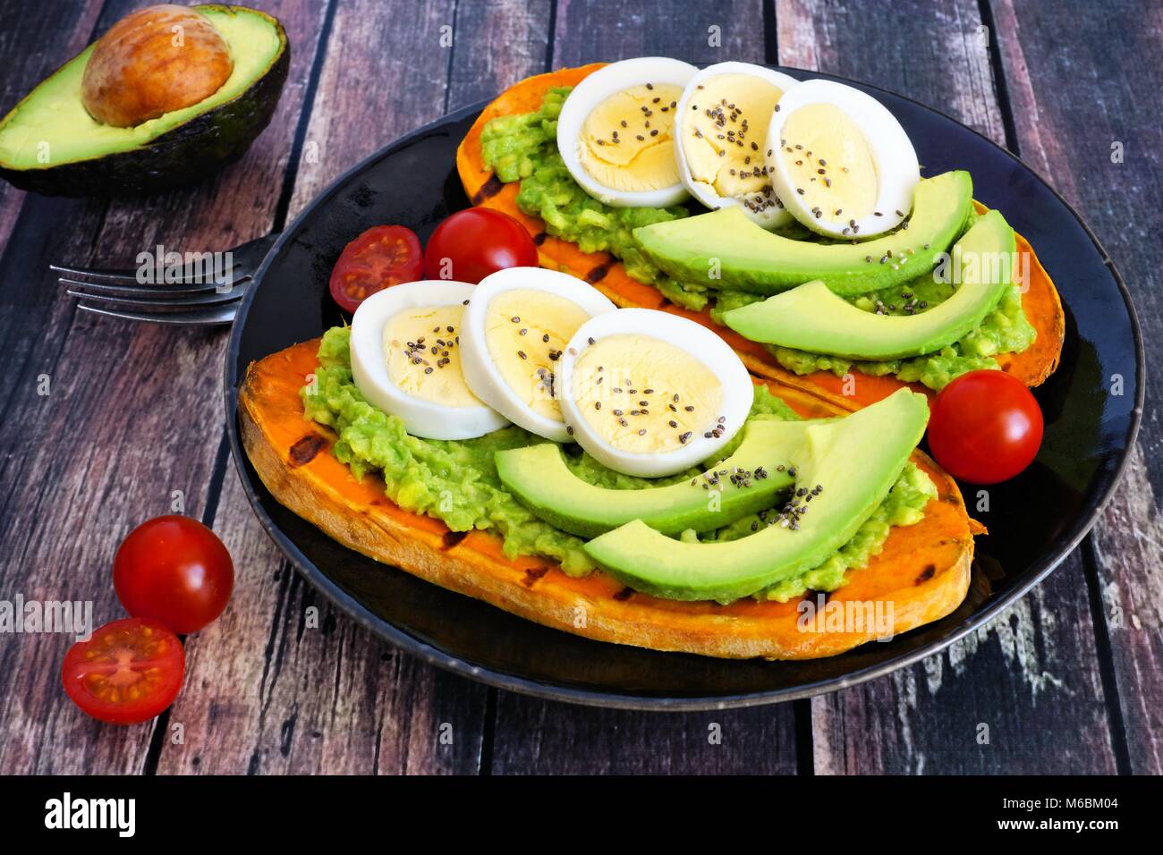 Süßkartoffel Toasts mit Avocado, Eier und Chia Samen auf einem dunklen Platte. Tabelle Szene mit einem hölzernen Hintergrund. Stockfoto