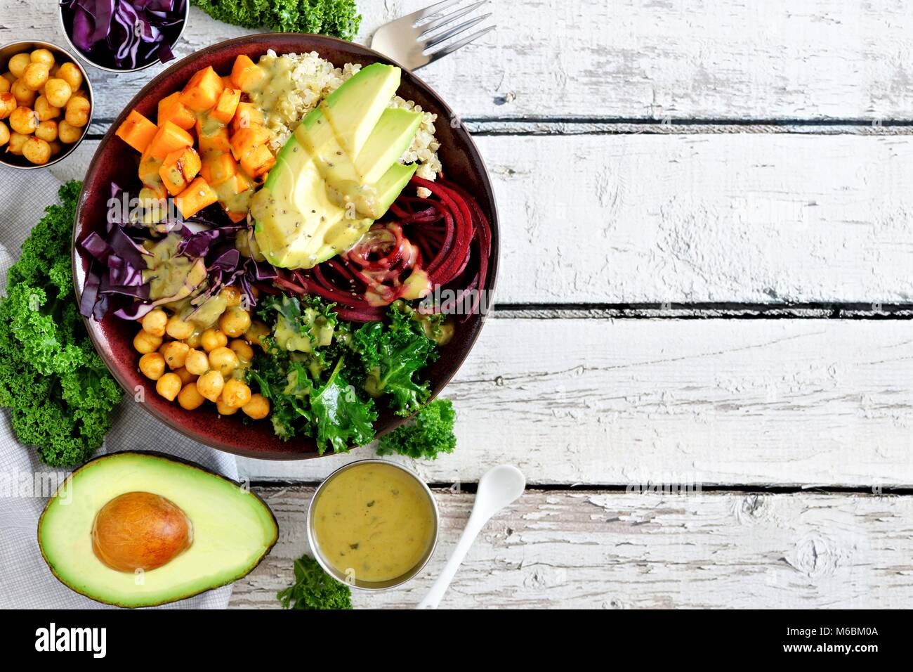 Buddha Schüssel mit Quinoa, Avocado, Kichererbsen, Gemüse auf einem weißen Holz Hintergrund, gesunde Ernährung Konzept. Ansicht von oben, seitliche Grenze zu kopieren. Stockfoto