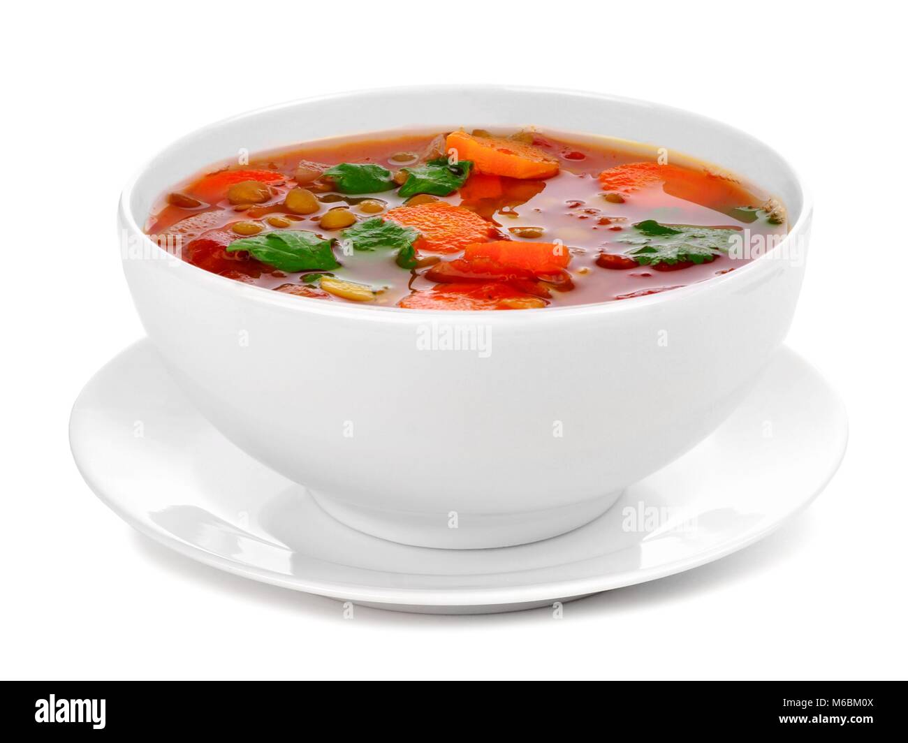 Hausgemachte Tomate, Linsensuppe in einer weißen Schüssel mit Untertasse. Seitliche Sicht auf einem weißen Hintergrund. Stockfoto