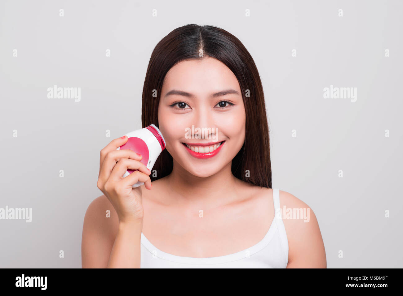 Junge asiatische Frau nutzt eine elektrische Bürste für tief reinigen Stockfoto