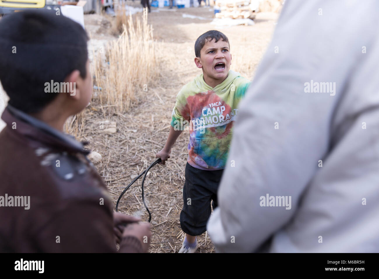 Mosul, Irak. 8. Dezember 2016 - ein Junge kämpft, versucht ein Mann mit einem Reifen Schlauch zu versuchen Beihilfen während einer United Distribution Nationen zu stehlen, Peitsche Stockfoto