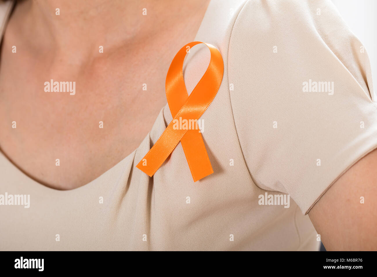 Nahaufnahme einer Frau mit Orange Ribbon zur Unterstützung der Nieren Krebs und Leukämie Bewusstsein Stockfoto