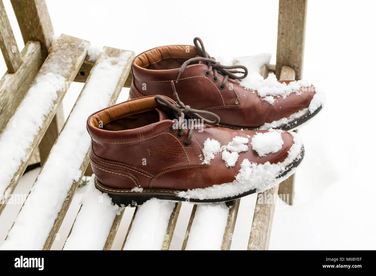 Schnee bedeckt Stiefel auf einen Garten Sitz. März 2018 Stockfoto