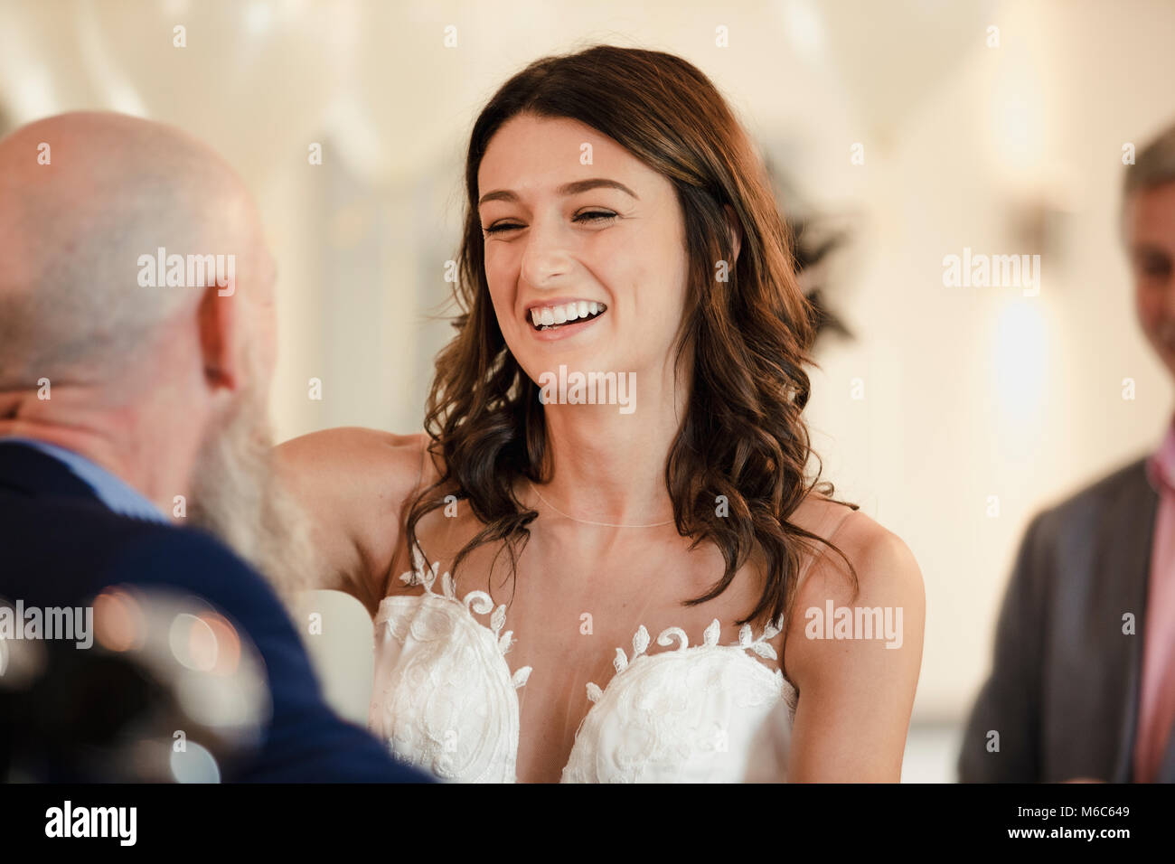 Schöne Braut ist in einem Tanz mit ihrem stolzen Vater. Sie werden lachen mit ihre Arme um einander. Stockfoto