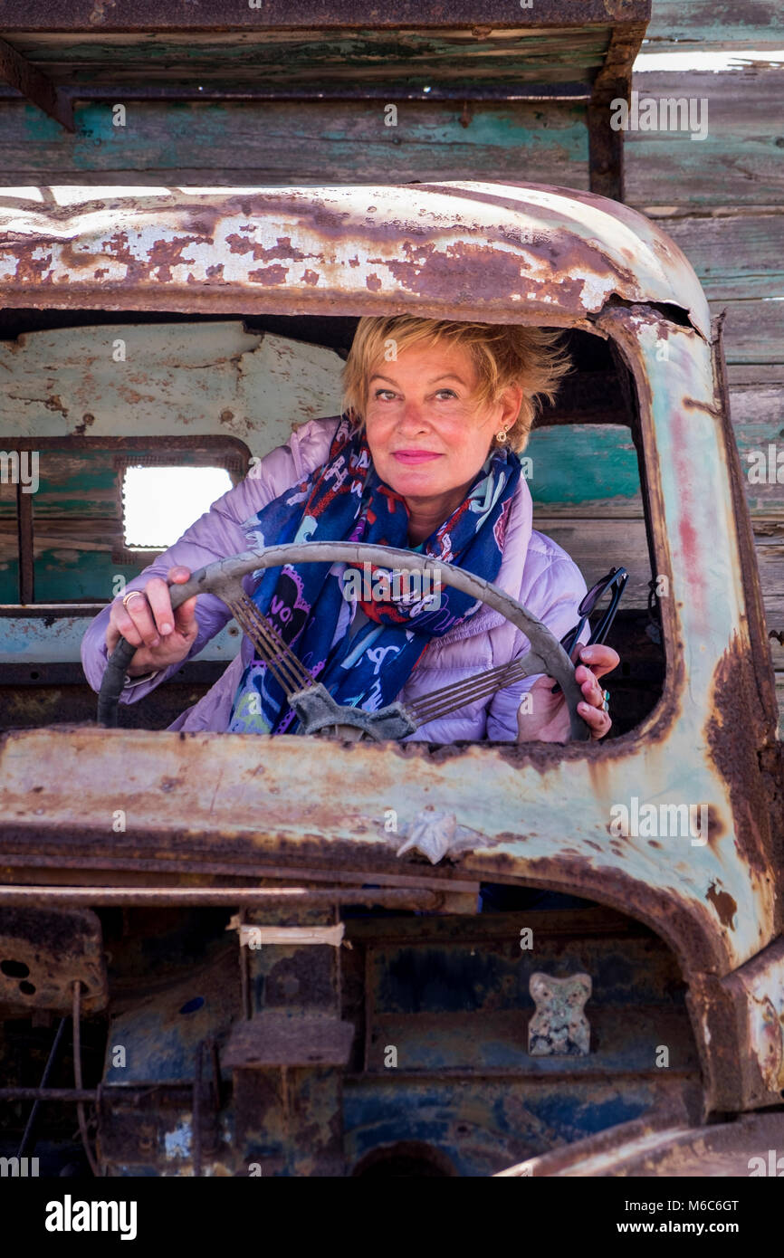 Elegante Frau gibt vor, eine ruinierte alte Lkw zu fahren Stockfoto