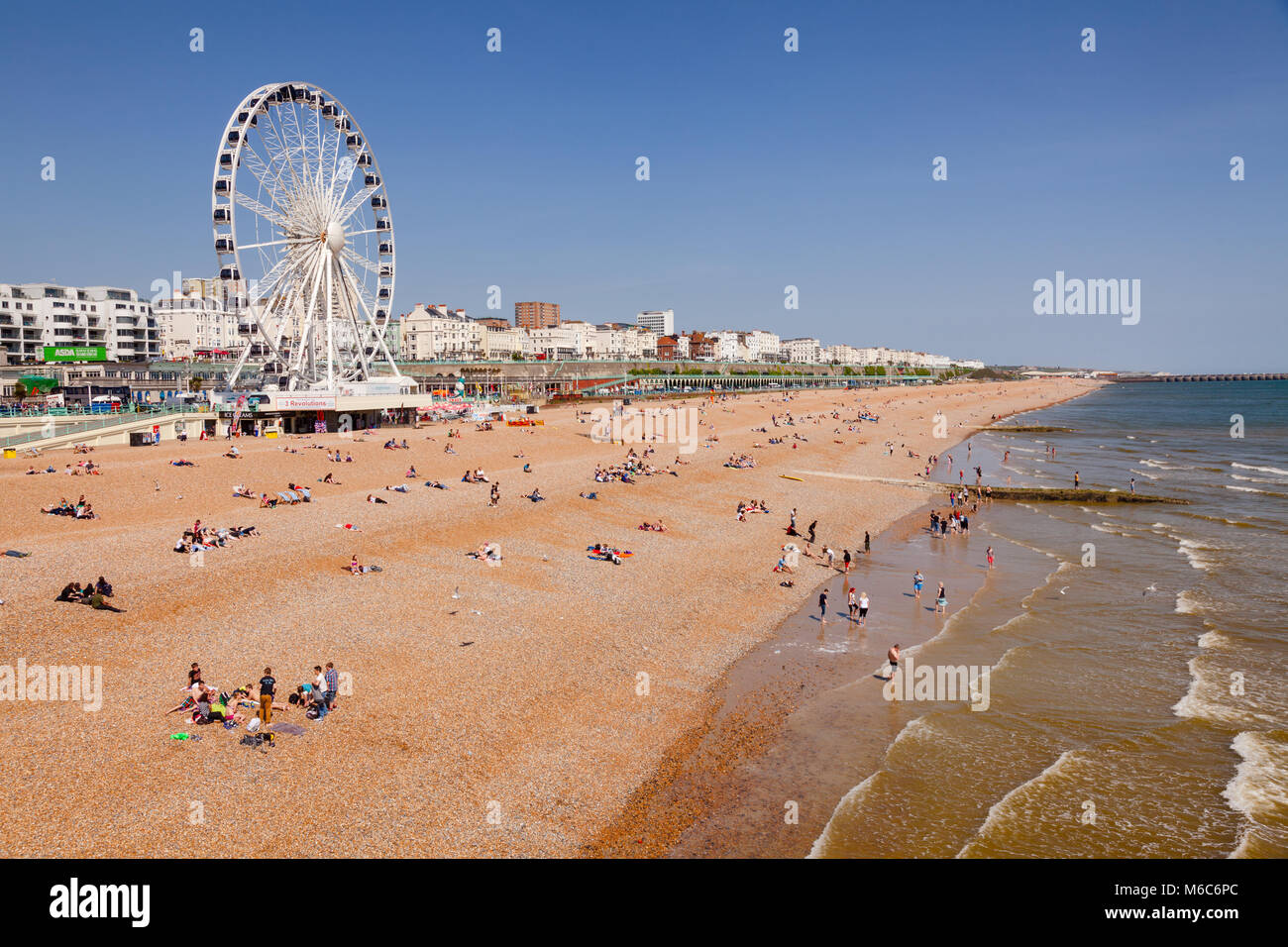 BRIGHTON, UK-Jun 5, 2013: Blick entlang der Strandpromenade von Brighton mit dem Riesenrad Promenade und Urlauber am Kiesstrand im Bild von der Hell Stockfoto