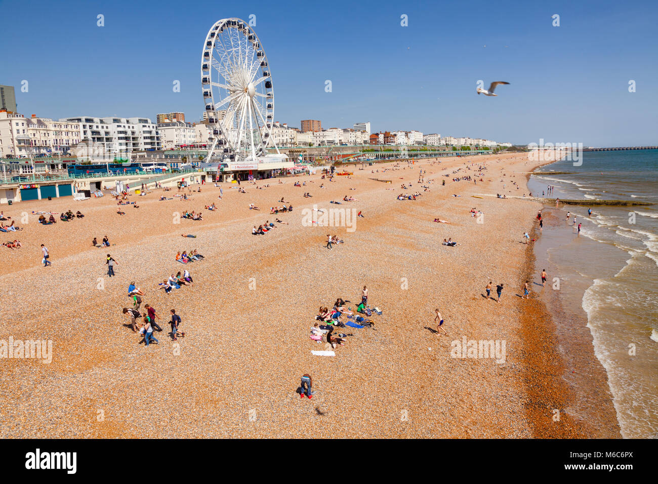 BRIGHTON, UK-Jun 5, 2013: Blick entlang der Strandpromenade von Brighton mit dem Riesenrad Promenade und Urlauber am Kiesstrand im Bild von der Hell Stockfoto