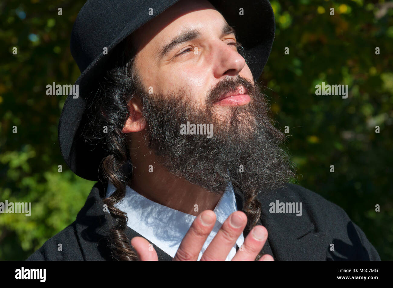 Außenbereich sonnige Porträt einer jungen gerne Beten traditionellen orthodoxen jüdischen Mann mit Brille und schwarzen Bart, Hut und Kostüm Stockfoto
