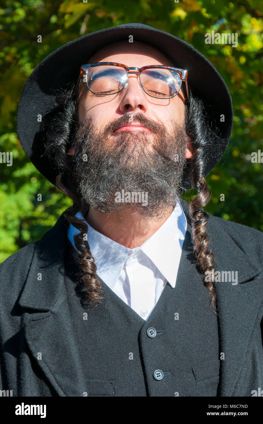 Außenbereich sonnige Porträt einer jungen Meditieren orthodoxen jüdischen Mann Brille tragen mit geschlossenen Augen Stockfoto