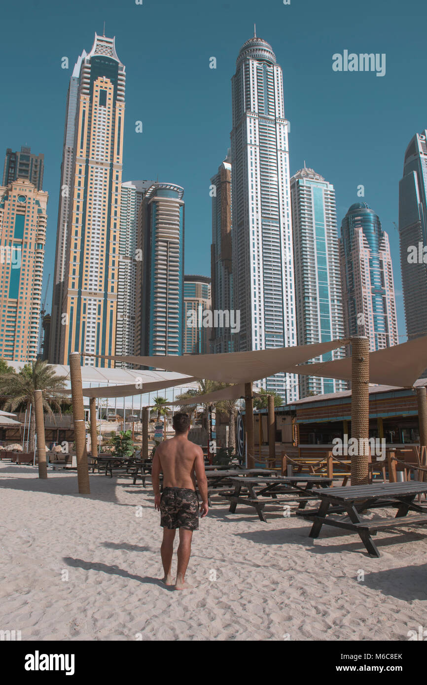 Mann am Strand mit Wolkenkratzern im Hintergrund Stockfoto
