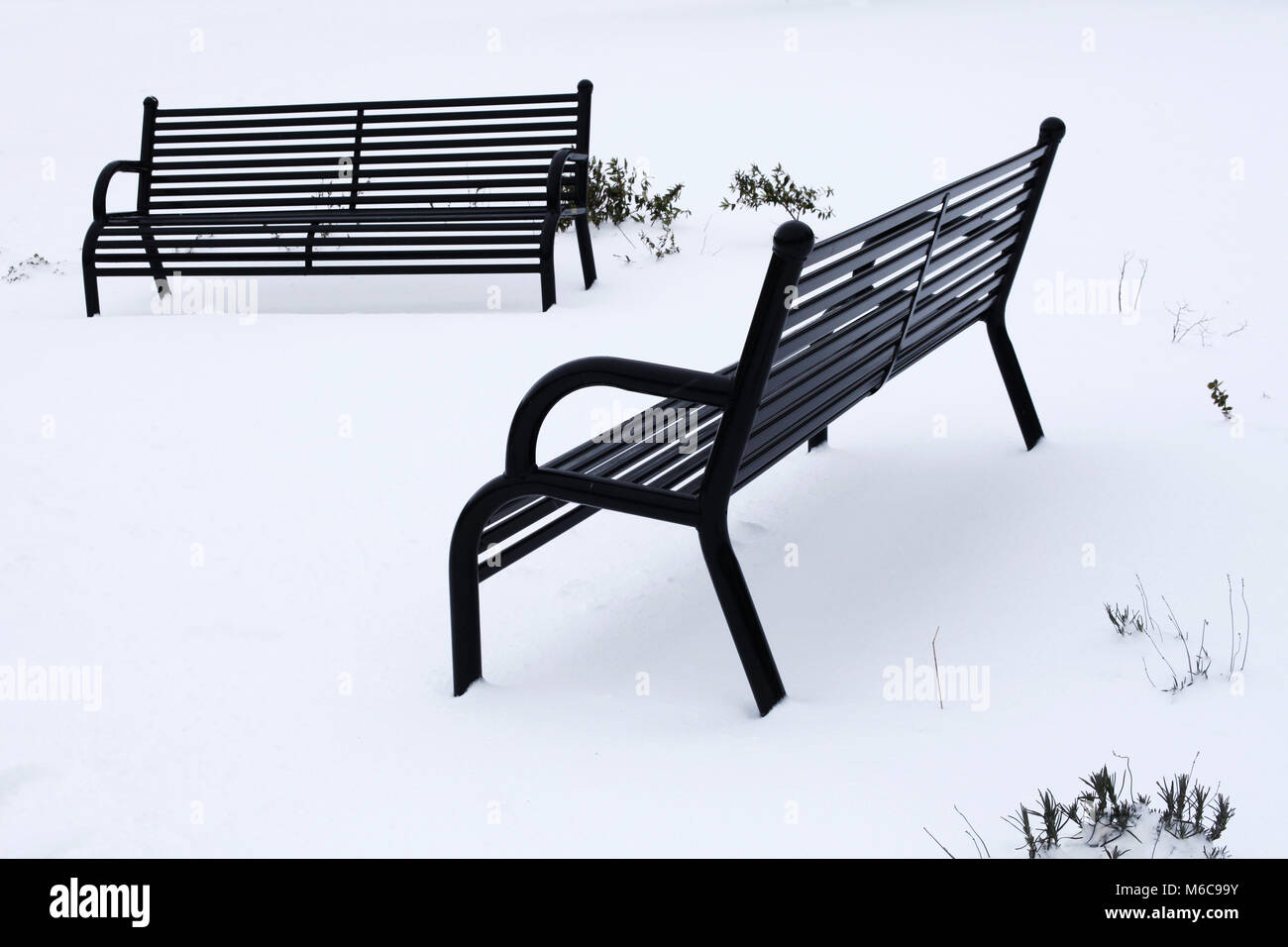 Zwei schwarze Parkbänke Erstellen einer abstrakten Blick auf schneebedeckte Gras Stockfoto