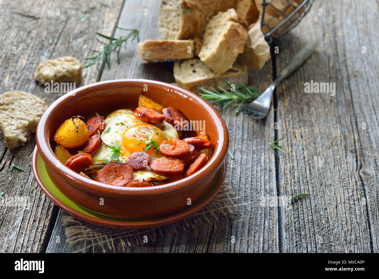 Spanische Tapa: Würzig Chorizo Wurst mit Spiegelei und Kartoffeln in einem Terra Cotta cazuela Gericht serviert. Stockfoto