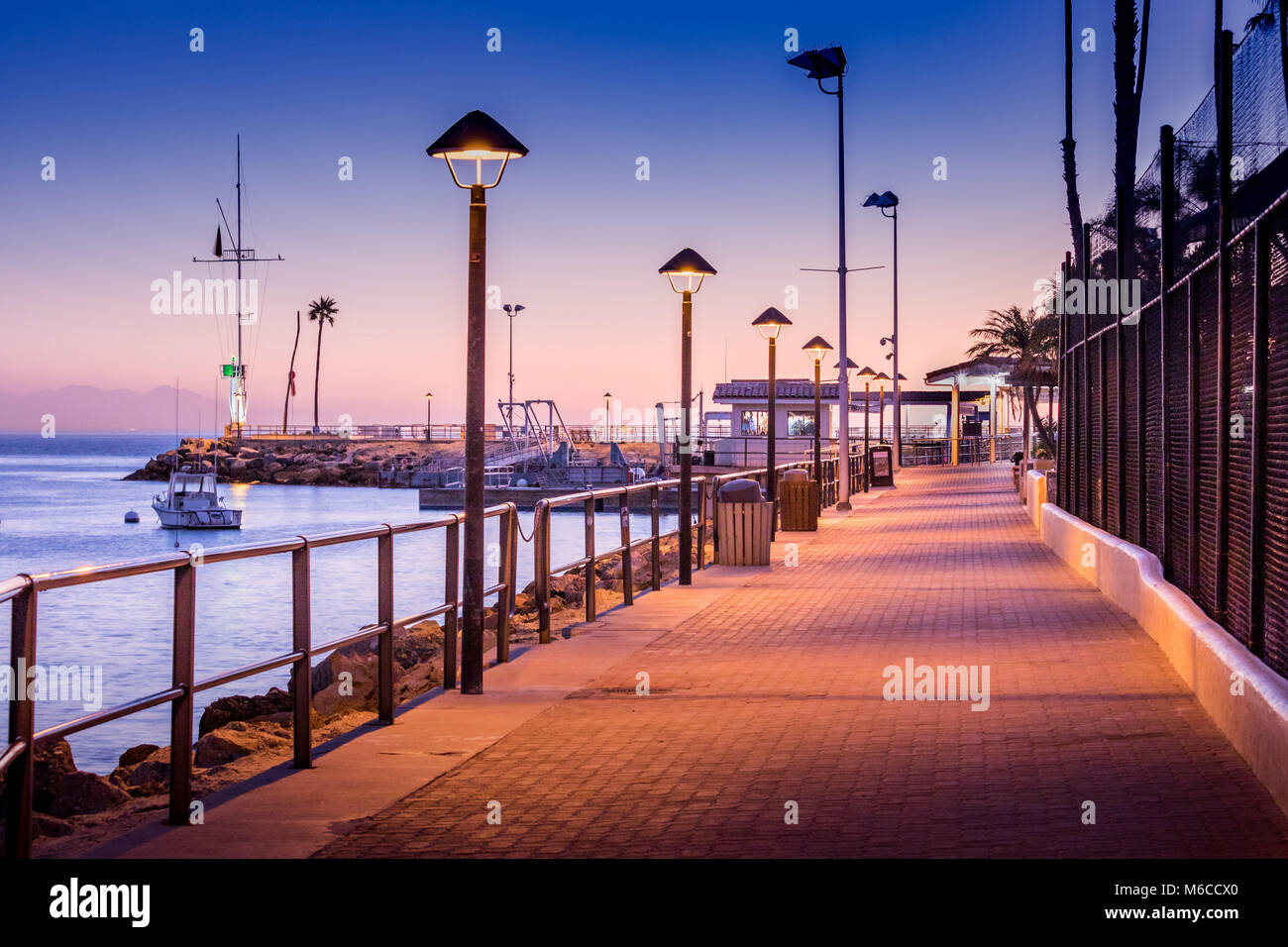 Brick Gehweg zu Boot Dock in frühen Morgen Sonnenaufgang Licht, Straßenbeleuchtung auf, Schatten, stillen und ruhigen friedlichen, Avalon, Santa Catalina Island, Kalifornien Stockfoto