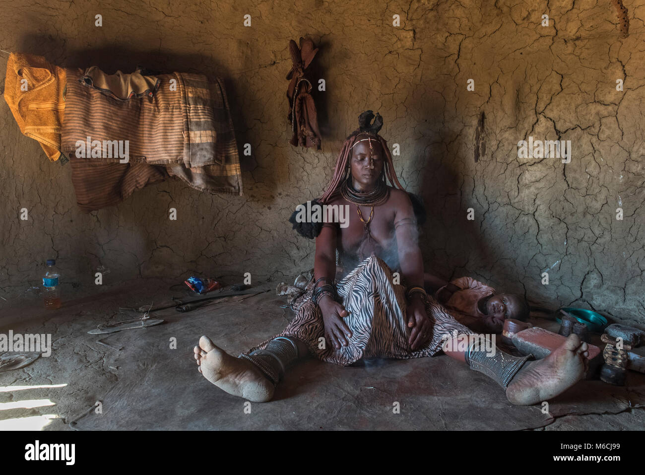 Frau der Ovahimba oder Himba Volk Reinigung und Desinfektion von Kleidung und Körper, Kunene, Namibia Stockfoto
