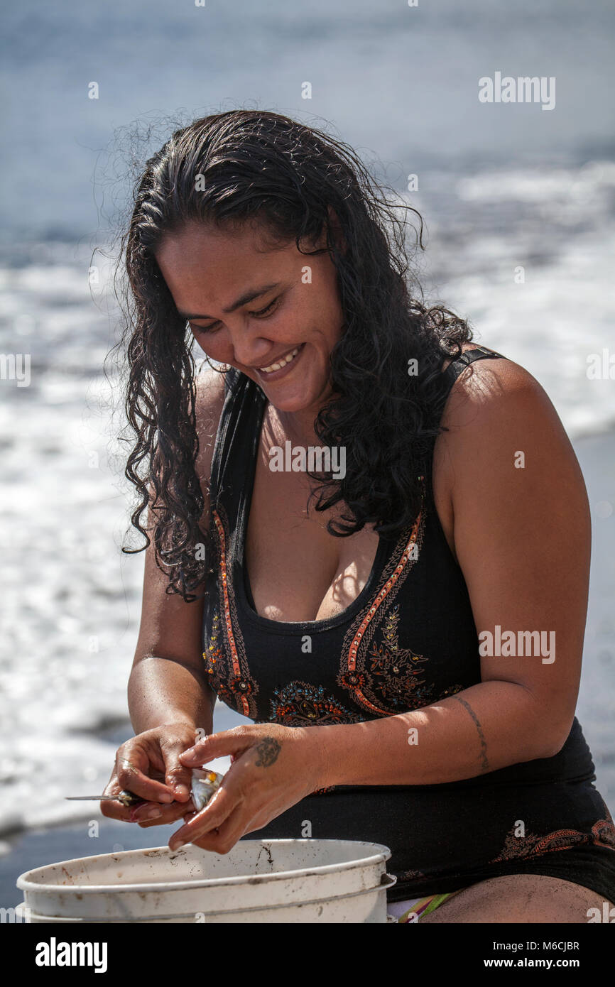 Frau, polynesische, lacht, reinigt Fisch am Strand, Badeanzug, Tahiti, Französisch-Polynesien Stockfoto