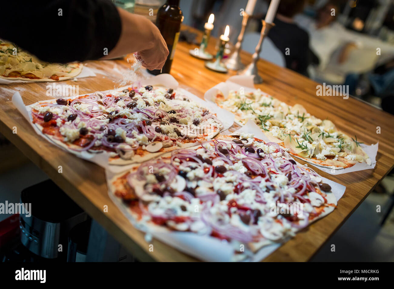 Weibliche Hand ist Richtfest ein Haus Pizza mit geriebenem Parmesan. Stockfoto