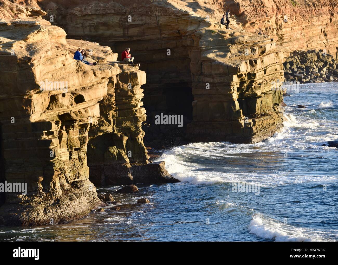 Menschen, die sich an steilen Klippen goldenen Sonnenuntergang zu beobachten und zu brechenden Wellen unten, Sunset Cliffs, San Diego, Kalifornien, USA. Stockfoto