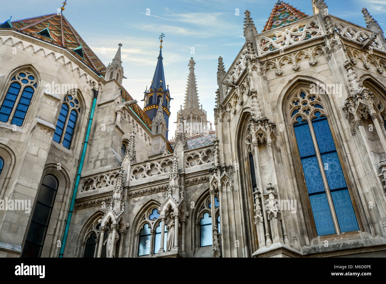 Die beeindruckende Fassade der Matthiaskirche in Budapest Ungarn wie die Sonne beginnt auf den Turmspitzen und Ziegeldach im Budaer Burgviertel zu setzen Stockfoto