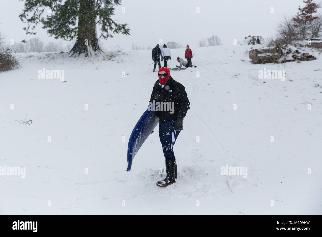 Celbridge, Kildare, Irland. 02 Mär 2018: Jugendliche mit Surf Board nach unten zu schieben Sie die Hügel mit Schnee bedeckt. Tier aus dem Osten durch Sturm Emma gefolgt brachte mehr Schnee und starke Winde in ganz Irland. Stockfoto