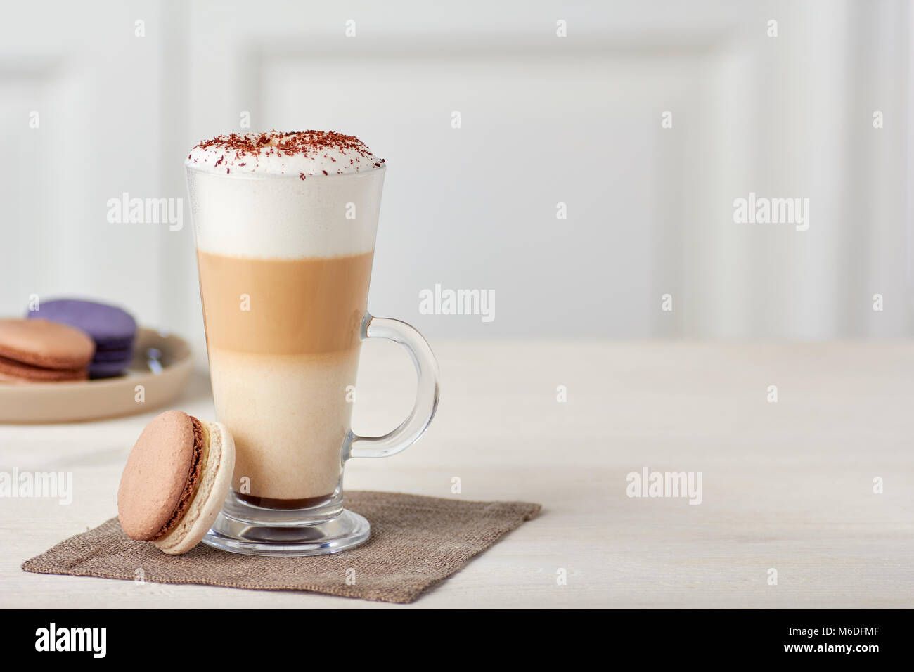 Glas Tasse Kaffee Latte und bunte Makronen auf hölzernen Tisch Stockfoto