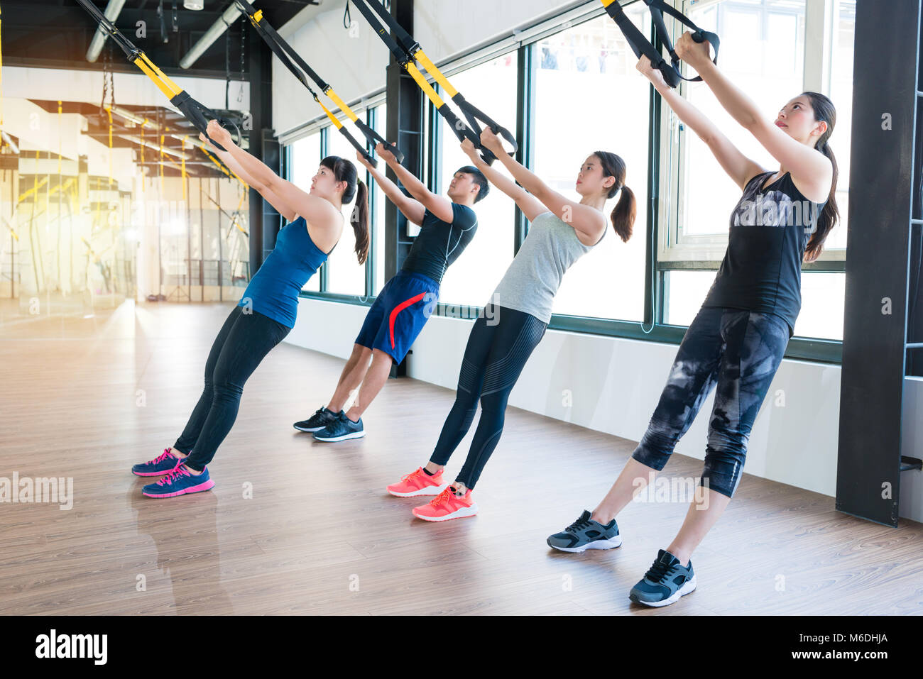Gruppe von Fitness TRX Suspension gurte Übungen asiatischen Menschen tun das Hochziehen, arbeiten mit eigenen Gewicht in eine sonnige helle Fitnessraum. Stockfoto