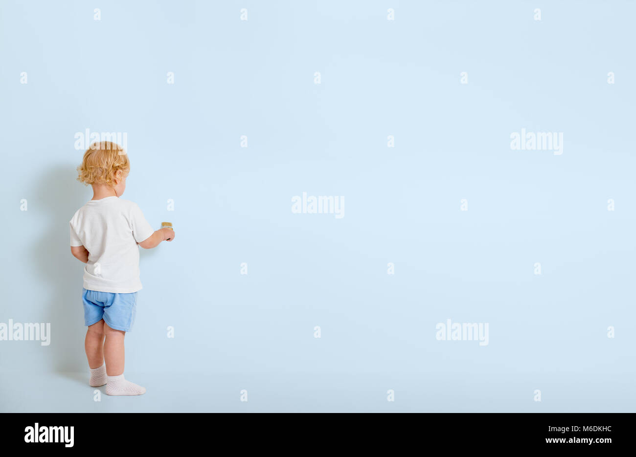 Junge mit Pinsel Rückansicht zurück in der Nähe von blauen Wand Stockfoto