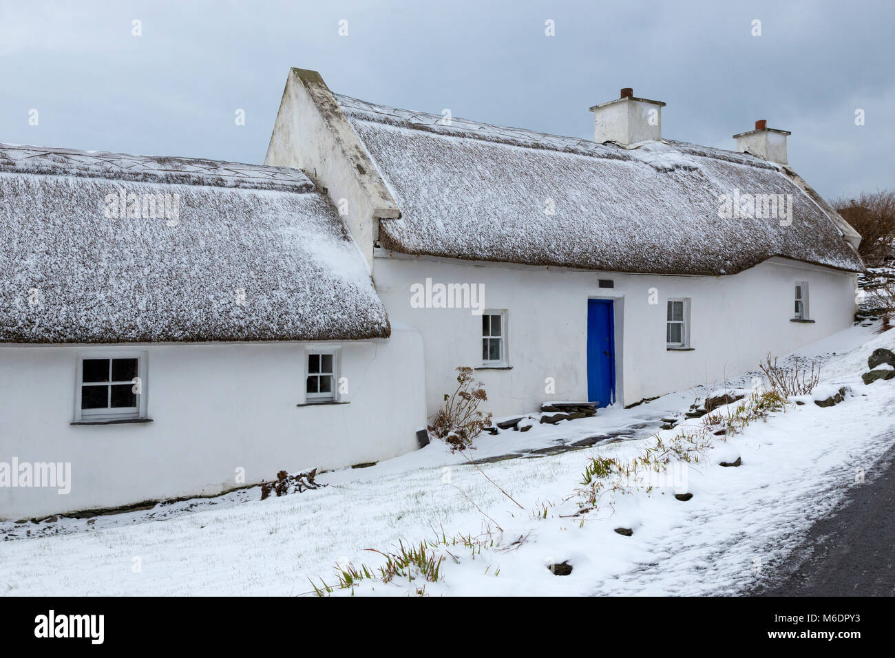 Schnee bedeckt strohgedeckten Irish cottage in country lane auf Valentia Island, County Kerry, Irland Stockfoto
