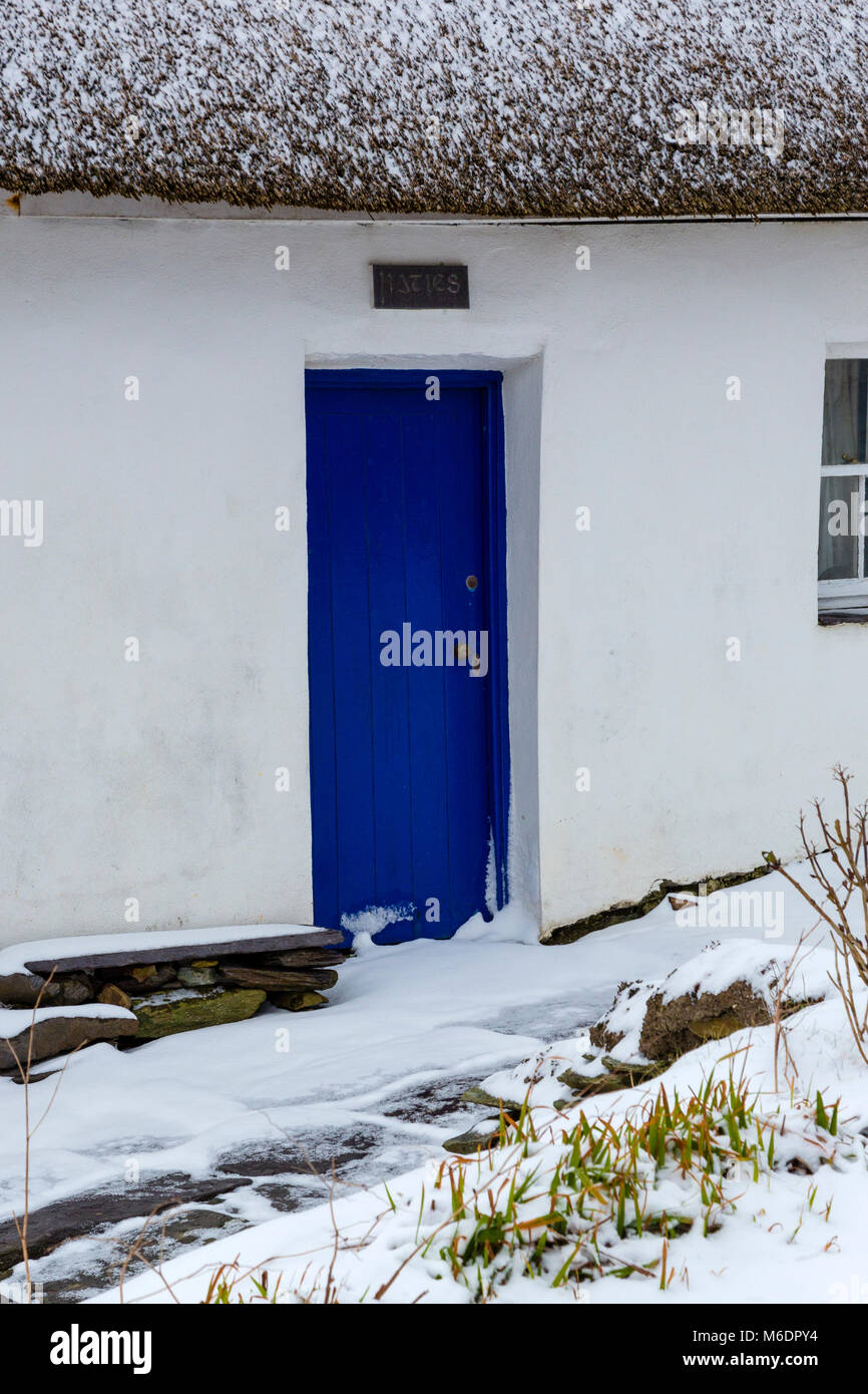 Schnee bedeckt strohgedeckten Irish cottage in country lane auf Valentia Island, County Kerry, Irland Stockfoto