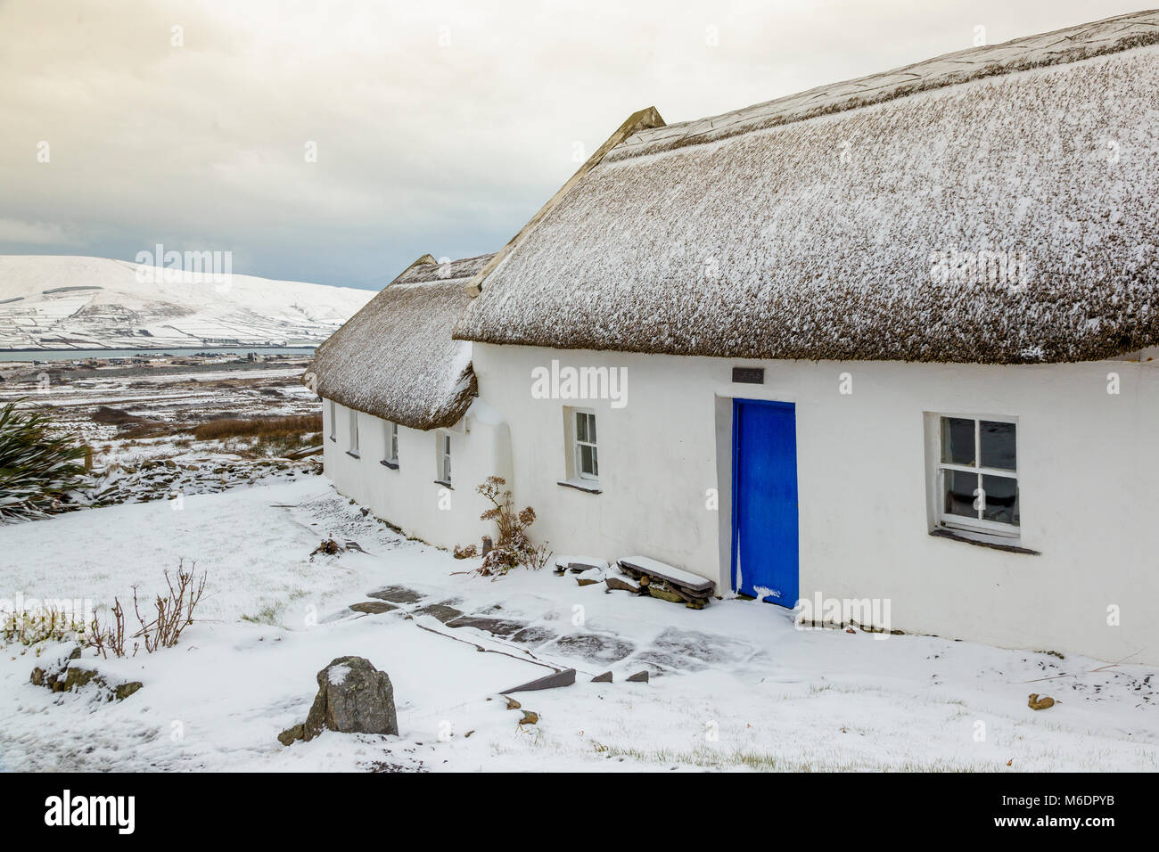 Schnee bedeckt strohgedeckten Irish cottage in country lane auf Valentia Island, County Kerry, Irland Stockfoto