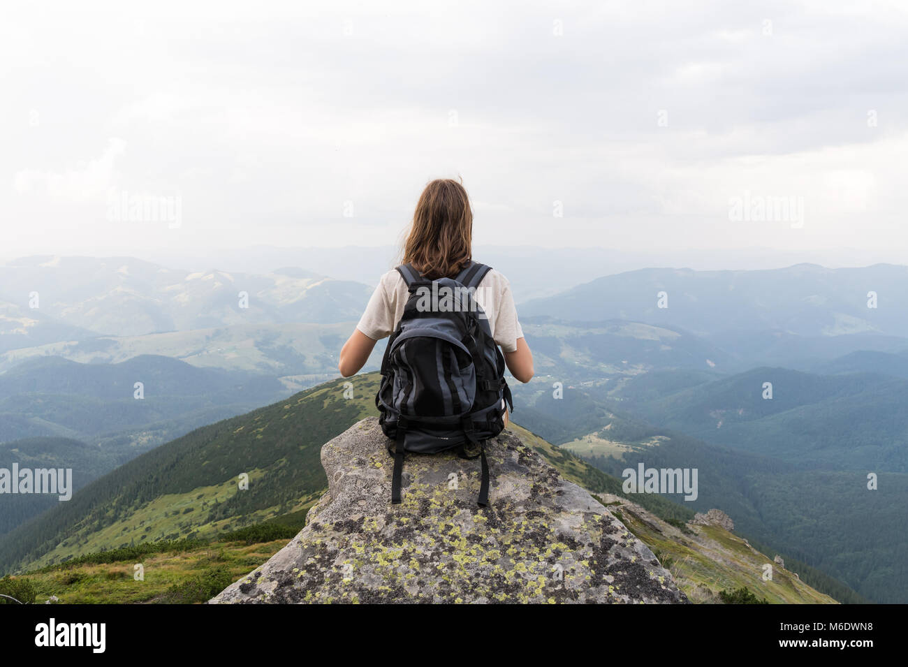 Mädchen Wanderer sitzt auf Felsen in der wunderschönen Bergwelt und sieht in endlosen Abstand Stockfoto