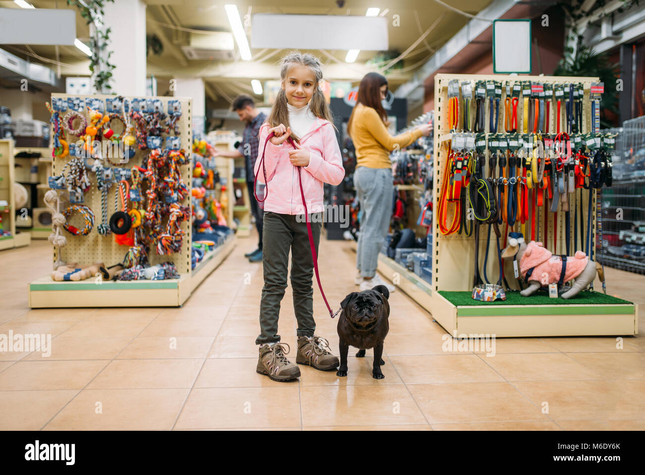 Kleines Mädchen mit Hund in Pet Shop, Freundschaft. Kind mit Hund wählt Zubehör in petshop, Pflege für Haustiere Stockfoto