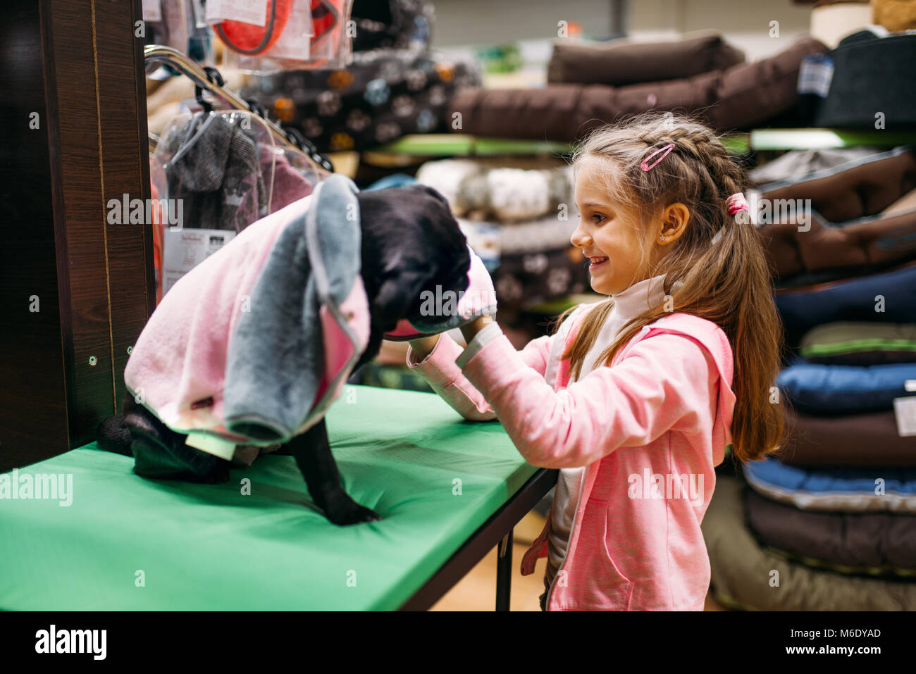 Kleines Mädchen wählt Kleidung für Welpen in Pet Shop. Kid Kunden kaufen Hunde insgesamt in petshop, für den inländischen Tiere Stockfoto