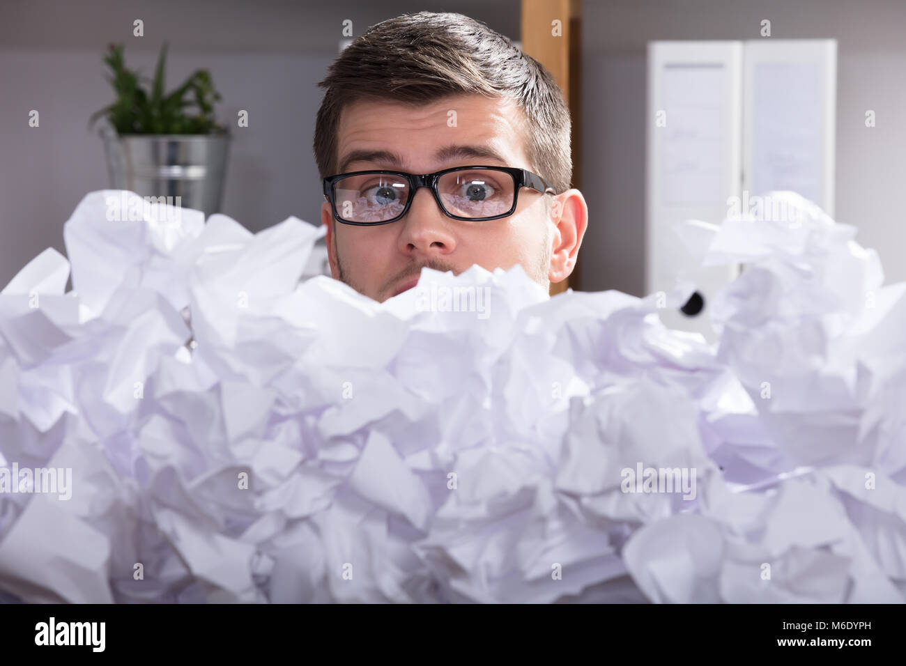 Nahaufnahme eines Geschäftsmannes Tragen einer Brille im Heap Suchen von Zerknittertes Papier Stockfoto
