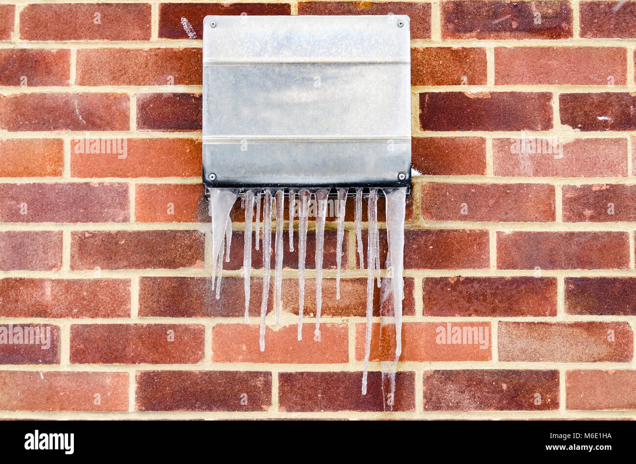 Eiszapfen hängen von der Außenseite Metall Abdeckung über einen Abzug von einem gaskessel. Stockfoto