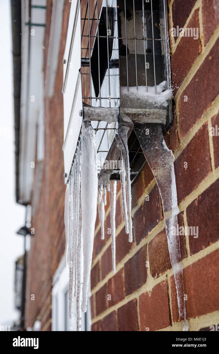 Eiszapfen hängen von der Außenseite Metall Abdeckung über einen Abzug von einem gaskessel. Stockfoto