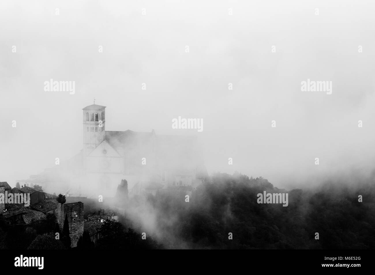 Blick auf die St. Francis päpstliche Kirche in Assisi (Umbrien, Italien) in der Mitte der Aufhebung Morgennebel Stockfoto
