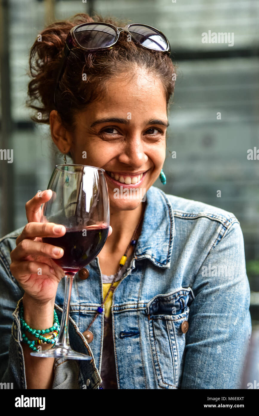 Schöne Latina Frau trinkt Rotwein und lächelnd Stockfoto