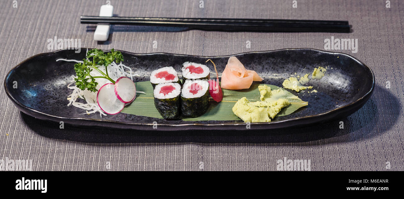 Maguro Thunfisch Sushi serviert auf einem Blatt, aus Bambus mit Radieschen und daikons Julienne, Ingwer und Meerrettich Wasabi, gari typisch japanisches Essen auf einem schwarzen di Stockfoto