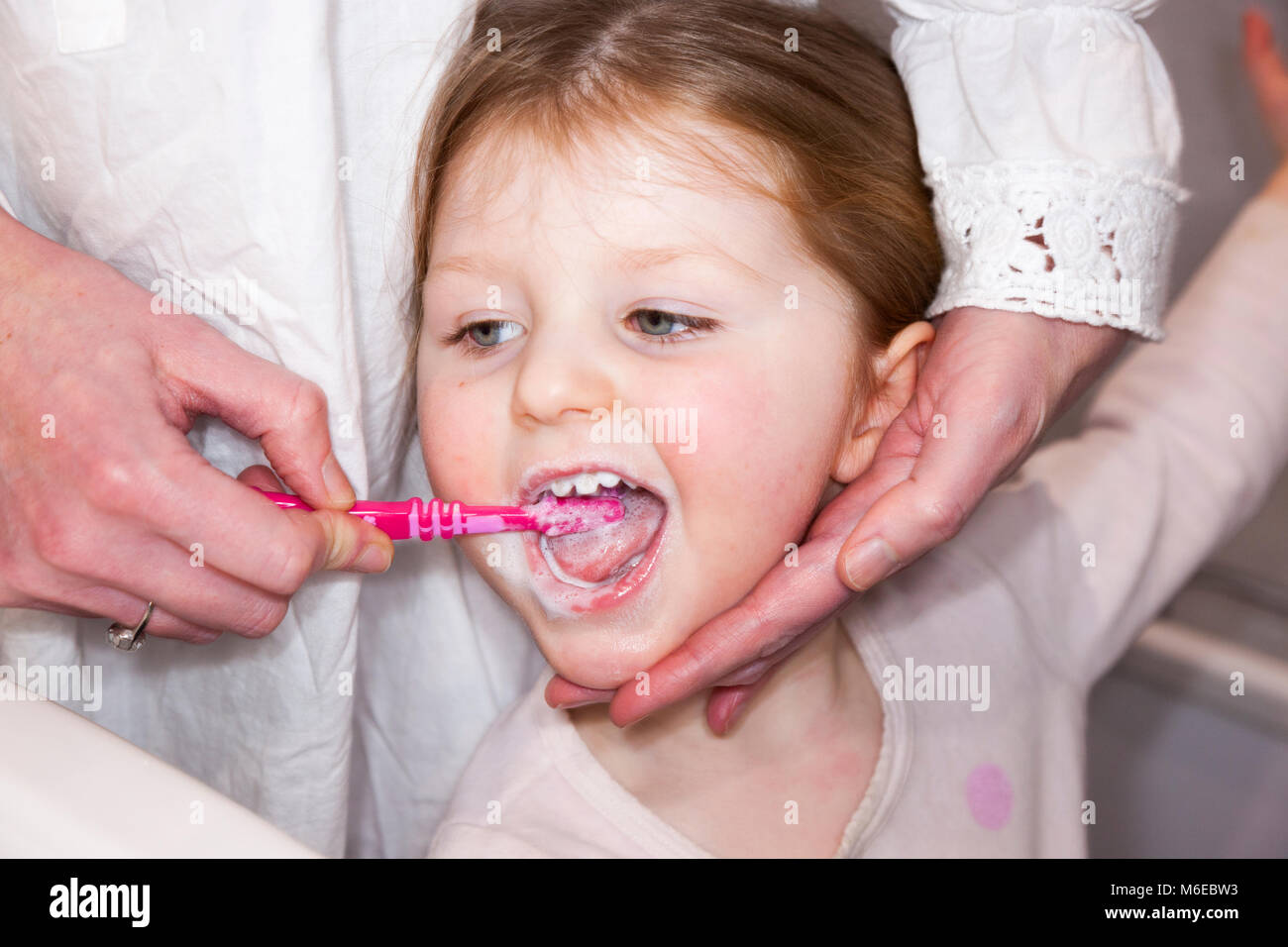 Drei Jahre alten Kind/Kind im Alter von 3 Jahren ihre Milch Zähne gebürstet mit einer Zahnbürste/Zahn Bürste mit - von ihrer Mutter/Mom/mom. Stockfoto