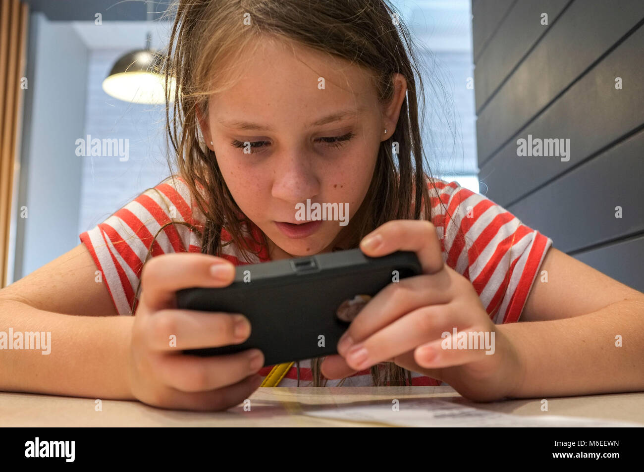 Junge Mädchen spielen mit einem Mobiltelefon, Indoor. Stockfoto
